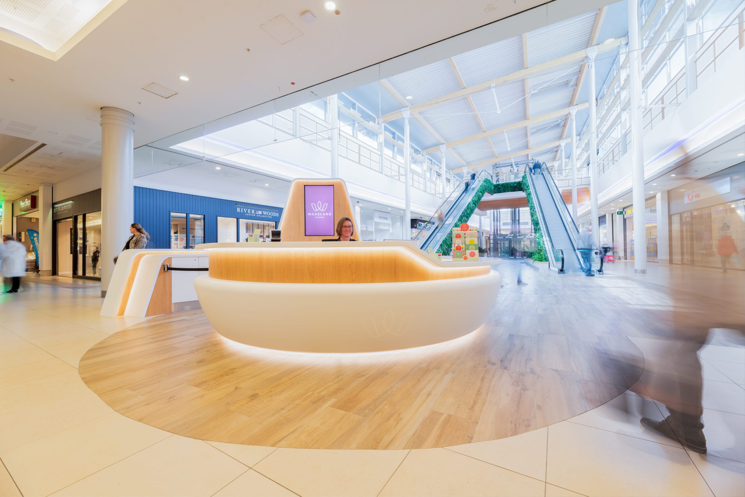 Redesigned information desk with panelled wood and neutral lighting &mdash; Waasland Shopping Centre, Belgium, Air Design